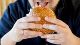 A man prepares to bite into a Burger King Whopper.
