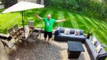 Thursday Night Mowing League member shows off his freshly mowed lawn while standing on his patio.