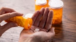 A person pours medication into their hand.