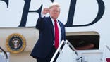 President Donald Trump holds up fist while boarding Air Force One