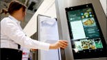 A woman opens a smart refrigerator.