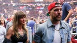 Taylor Swift and Travis Kelce seated courtside at an NBA Eastern Conference Finals basketball game.