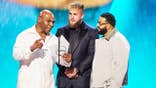 Mike Tyson, Jake Paul and DJ Khaled stand together on stage.