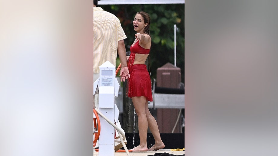 Shakira hablando con alguien y señalando algo, vestida con un bikini rojo en Miami, Florida.