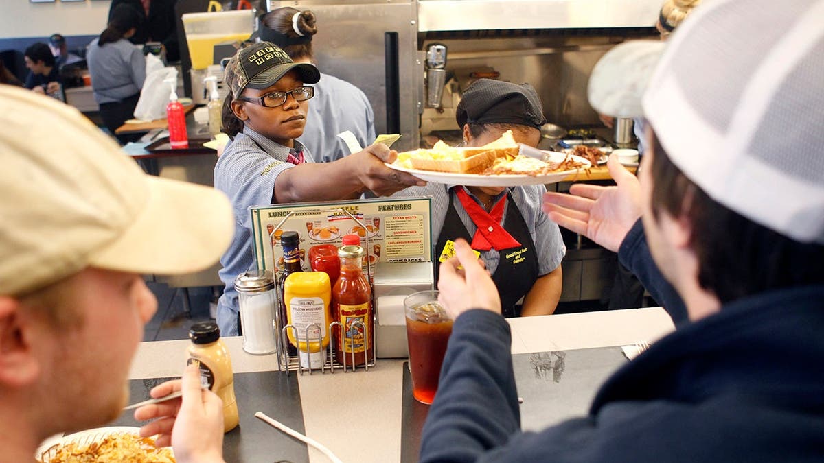 A server hands a plate of food to a customer at a crowded Waffle House restaurant.