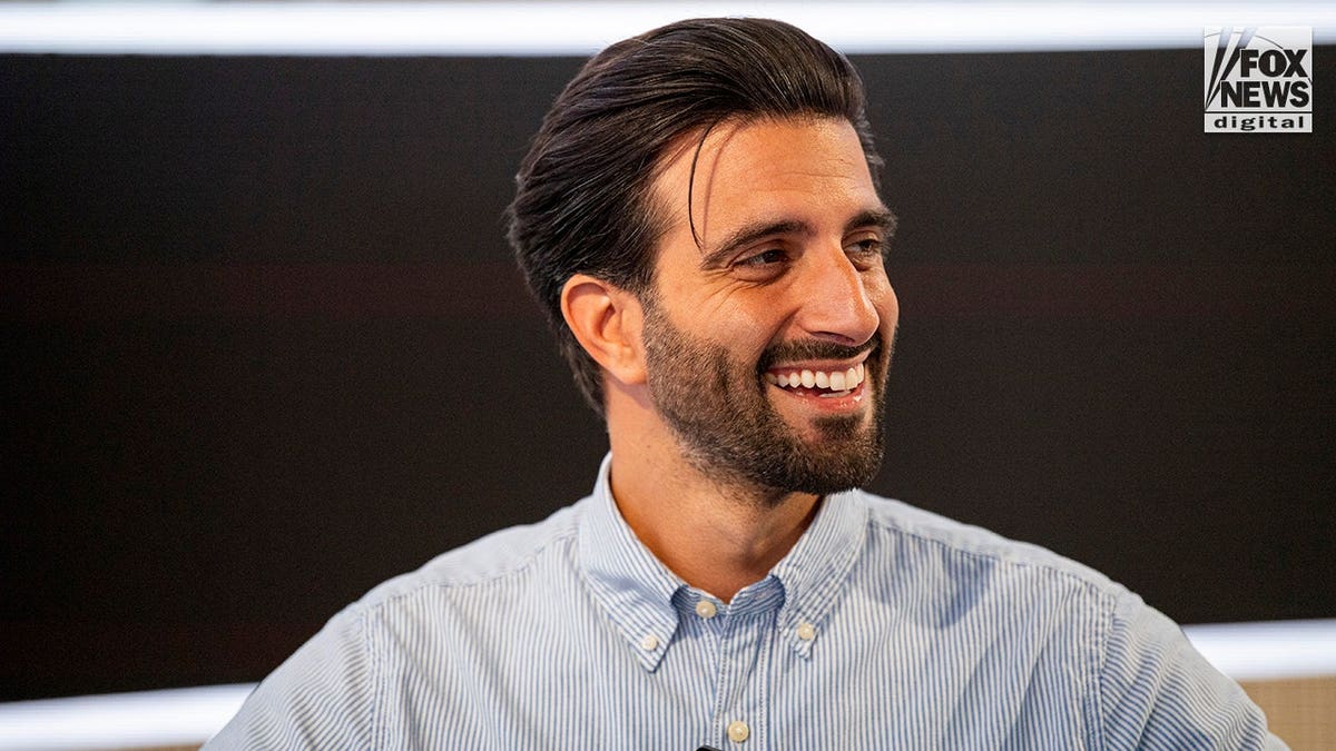 Davide De Pierro grins in a blue and white striped shirt.