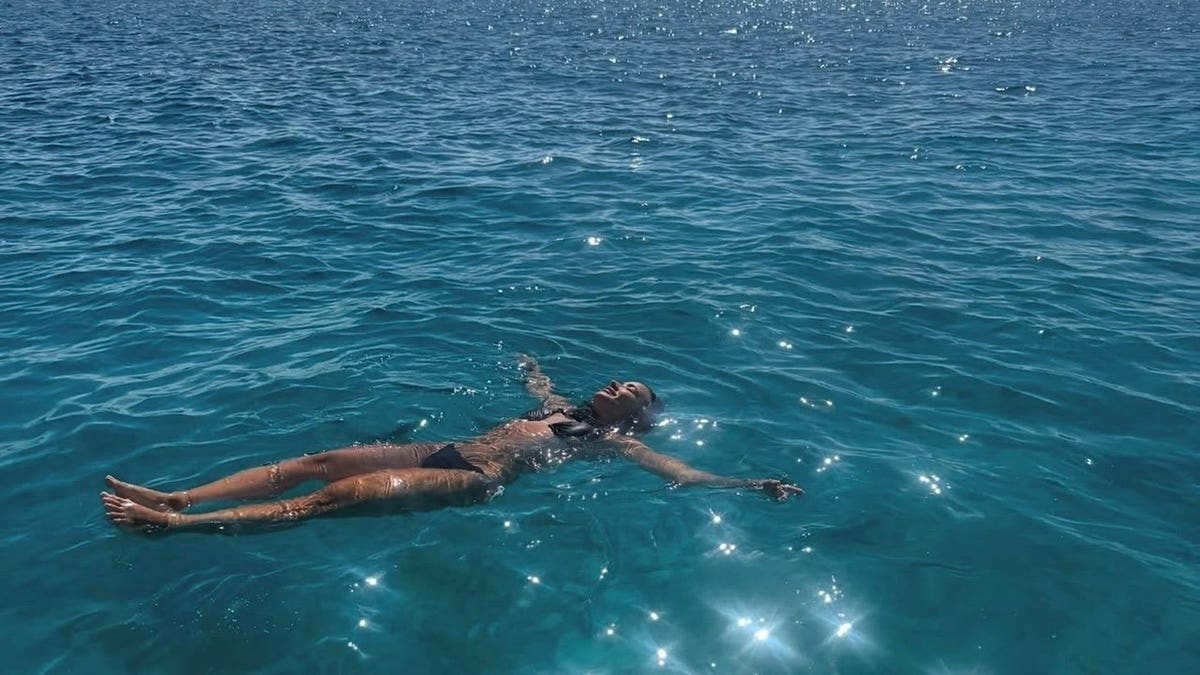 Demi Lovato floats on her back in clear water while wearing a red string bikini.