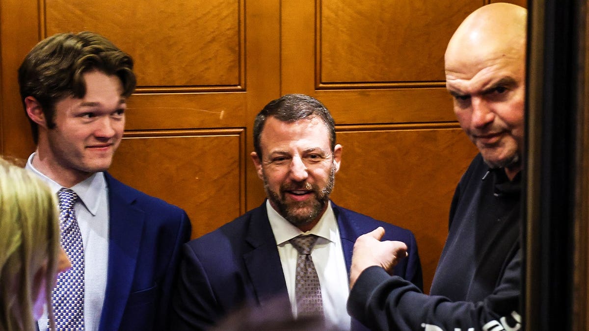 U.S. Sen. John Fetterman (D-PA) gestures to U.S. Sen. Markwayne Mullin (R-OK) as they stand in an elevator during a vote at the U.S. Capitol Building on March 12, 2026 in Washington, DC.