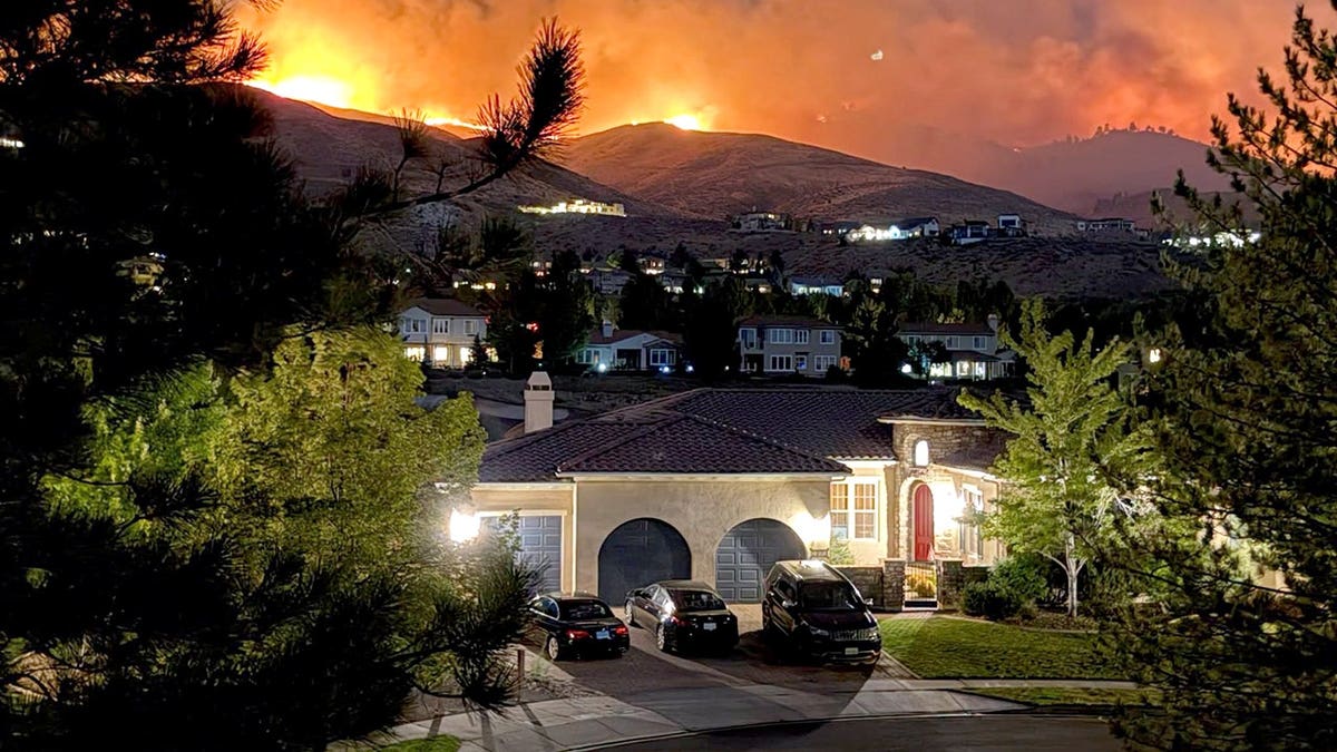 Flames burning in hills above a home