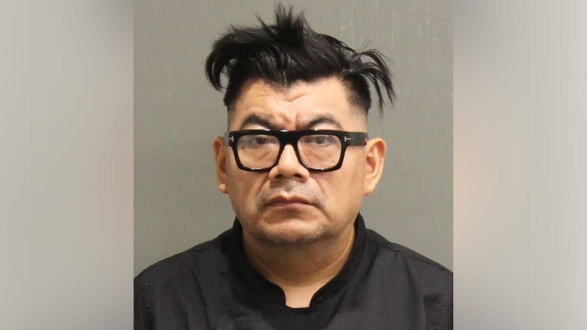 The booking photo of Felipe Alvarado Hernandez, a man with dark hair wearing black-framed glasses and a dark shirt.