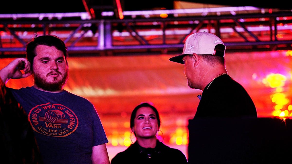 Jennifer Tedmori in black standing in between two men also wearing black at a concert.