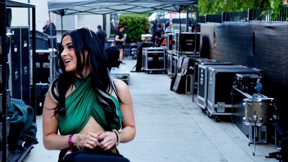 Jennifer Tedmori wearing a sparkling green top walking ahead of a concert while filming 