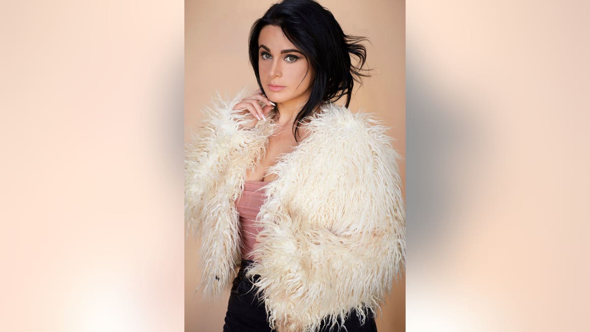 Jennifer Tedmori in a glamorous pose wearing a white furry coat.