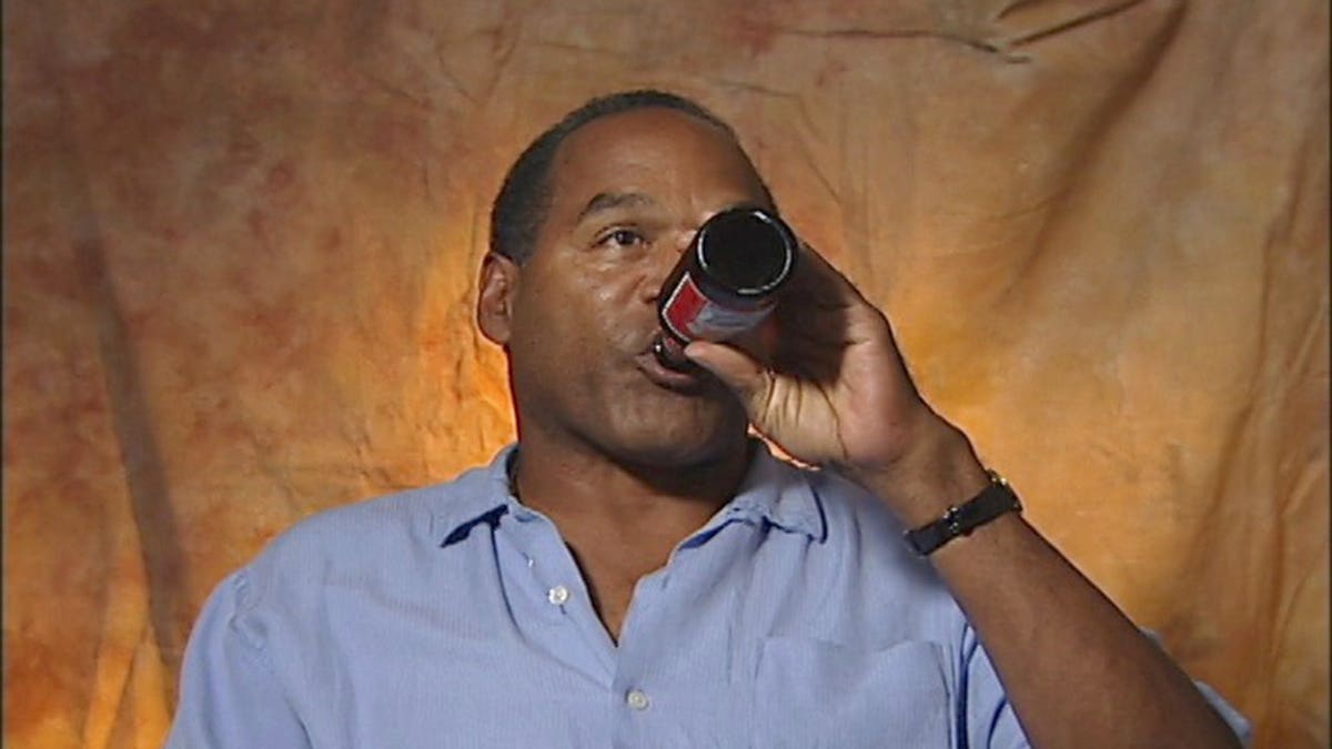O.J. Simpson in a blue shirt drinking a beer.