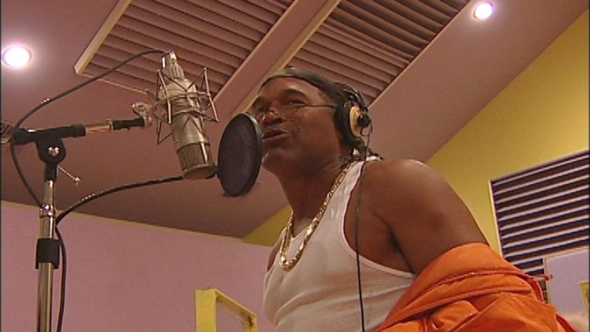 O..J. Simpson wearing a white tank top trying to rap.