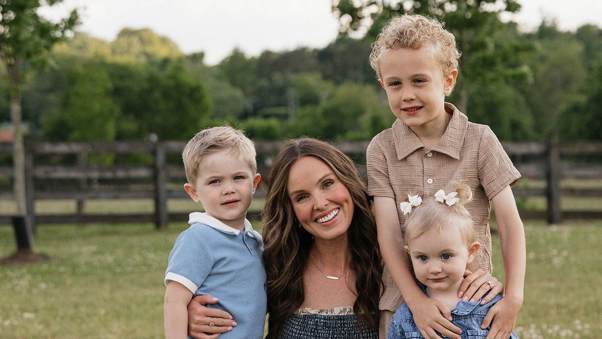 Jade Kircus smiling and embracing her three children.