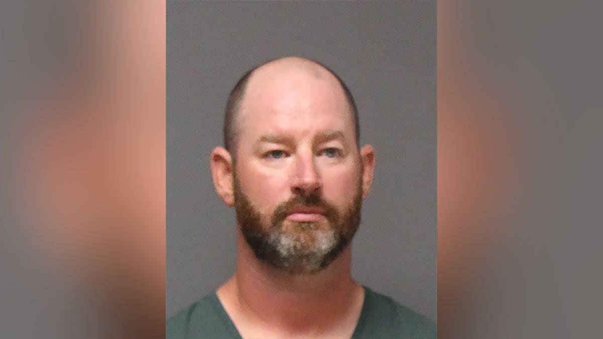 Mugshot of Kevin Wells wearing a green shirt against a gray background.