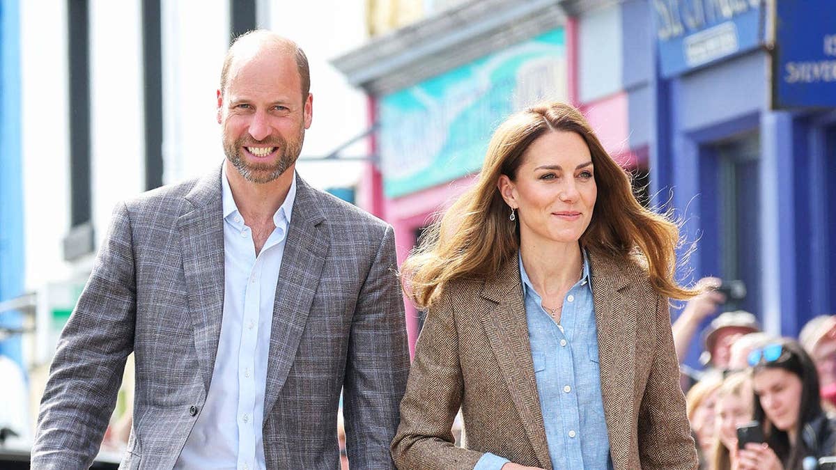 Prince William and Kate Middleton in suits greeting a crowd in Scotland.