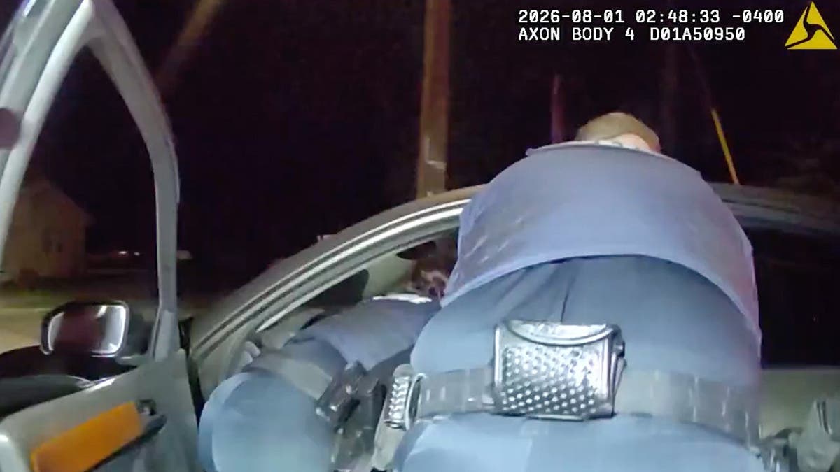image shows two officers reaching down into driver's seat