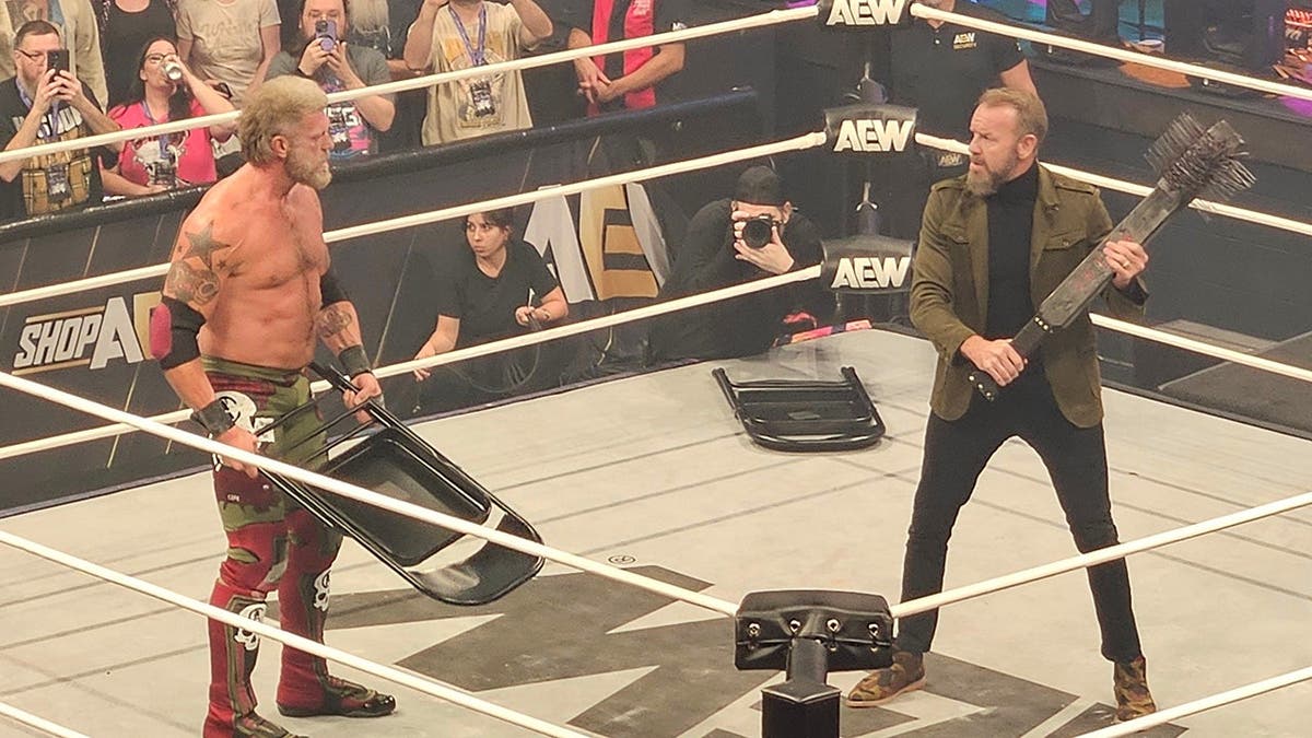 Adam Copeland and Christian Cage stand facing each other with weapons in hand.
