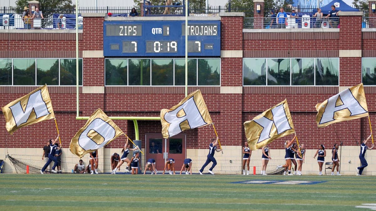 Akron Zips cheerleaders run flags through the end zone after a touchdown.