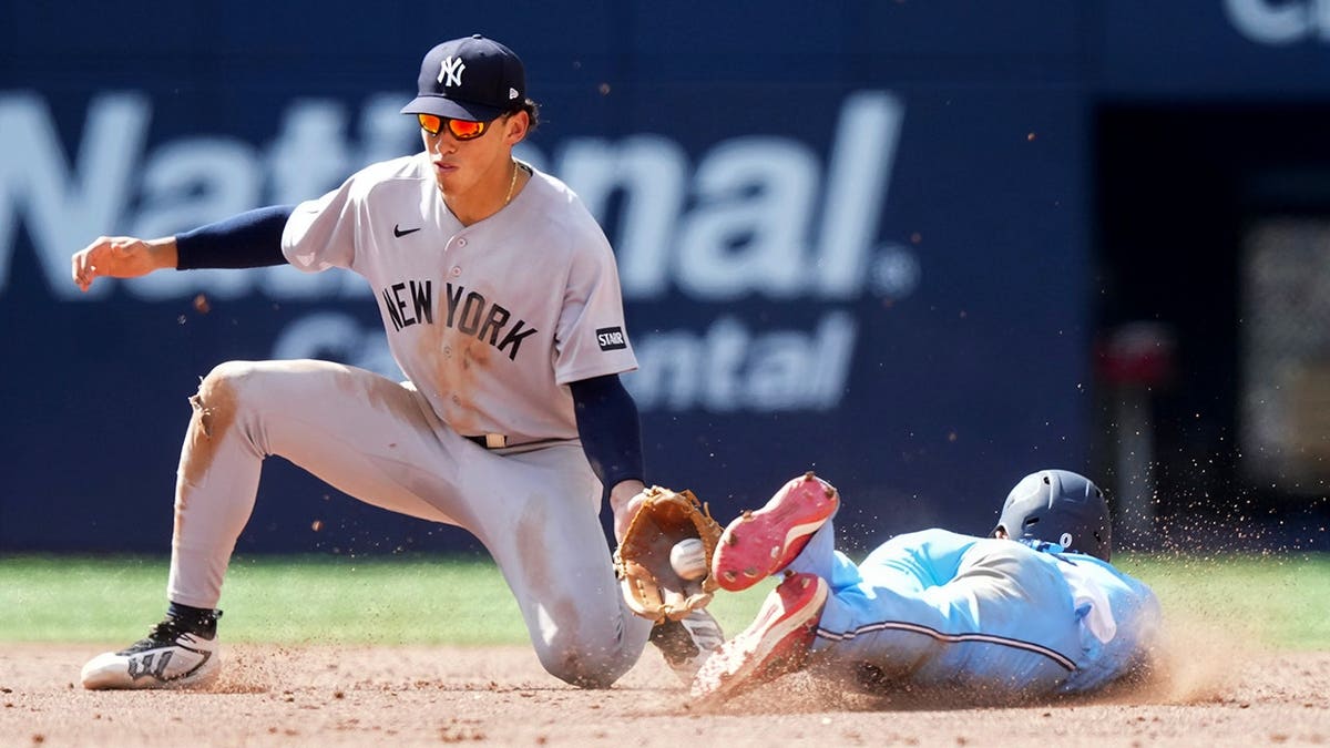 Andrés Giménez steals second base past Yankees shortstop George Lombard Jr. during a baseball game.