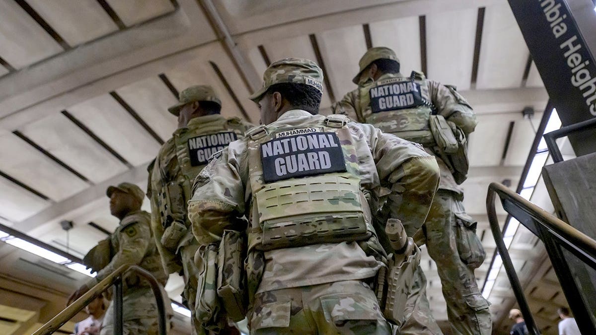 Arkansas National Guard members carry an elderly woman in a wheelchair down metro station steps.