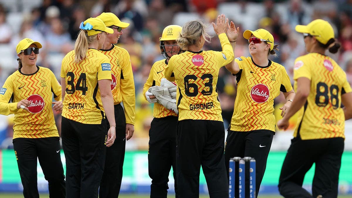 Ash Gardner celebrates with teammates after taking a wicket during a cricket match.