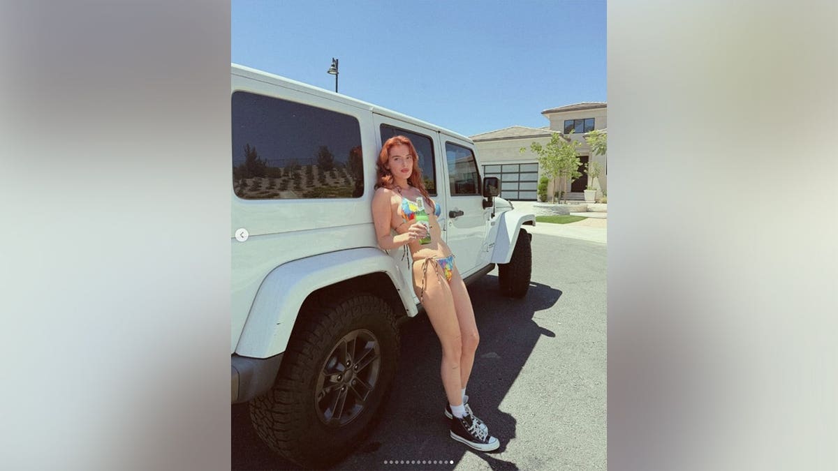 Bella Thorne leaning on a white jeep.