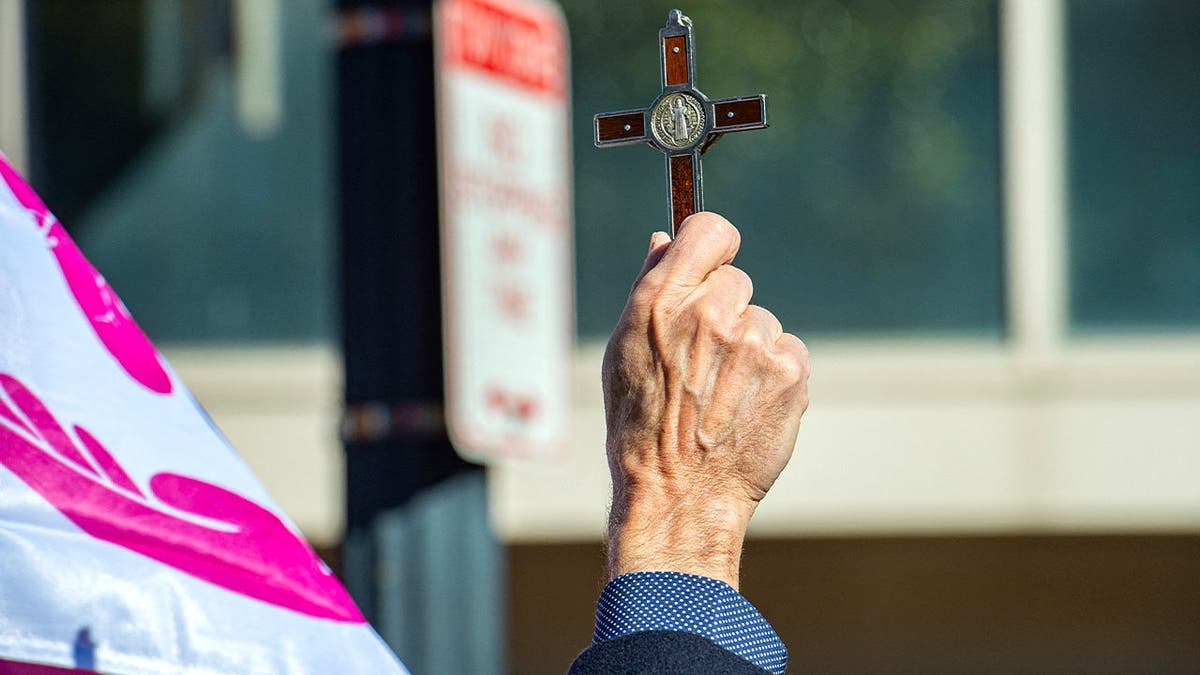 Pro-life demonstrator holds crucifix while praying outside Planned Parenthood.