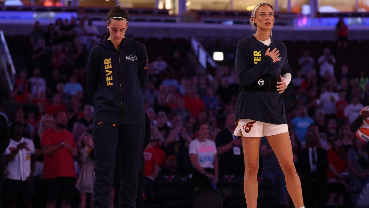 Caitlin Clark and Sophie Cunningham stand during the national anthem.
