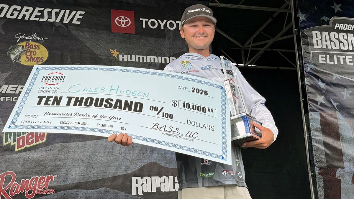 Caleb Hudson holds giant check and trophy after winning 2026 Bassmaster Rookie of the Year