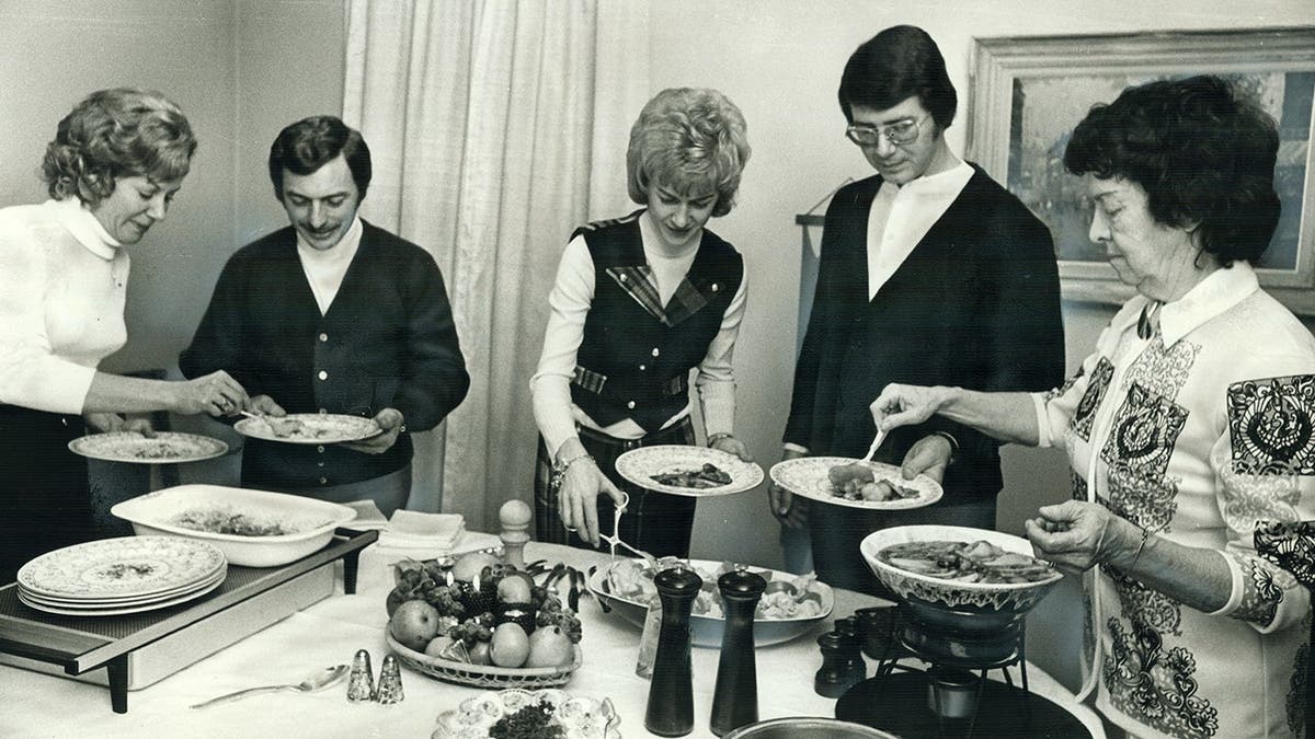 A group of friends enjoy a dinner party in the midcentury.