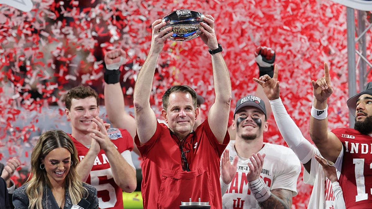 Curt Cignetti hoists the George P. Crumbley Trophy after Indiana's College Football Playoff semifinal victory.