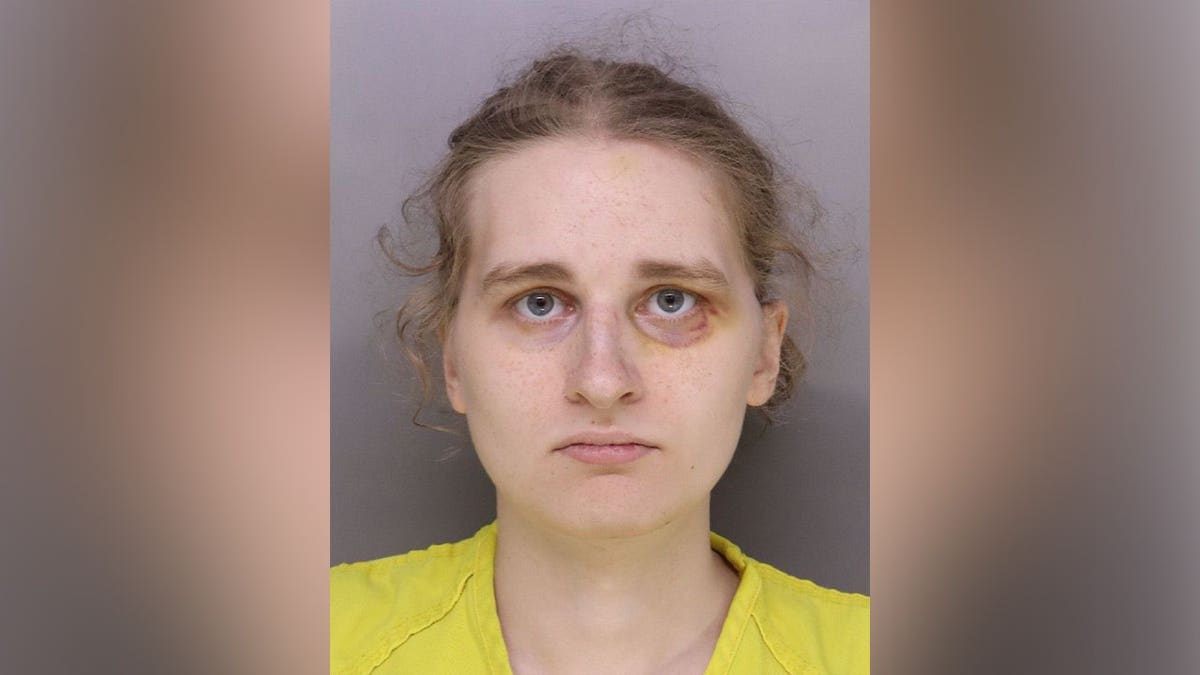  Booking photo of Nessa Keaney wearing a yellow jail uniform against a gray background.