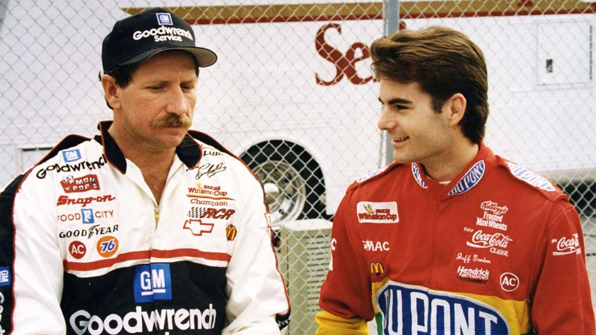 Dale Earnhardt and Jeff Gordon stand together discussing race strategies.