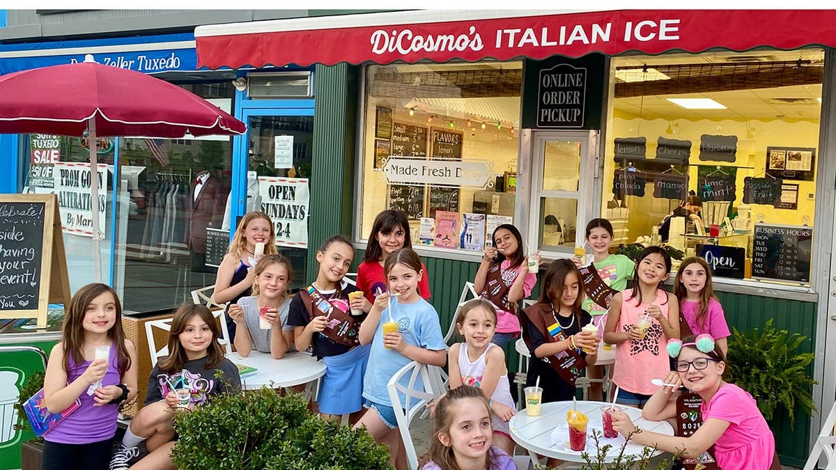 A group of kids eats Italian ice outside of DiCosmo's Italian Ice shop.