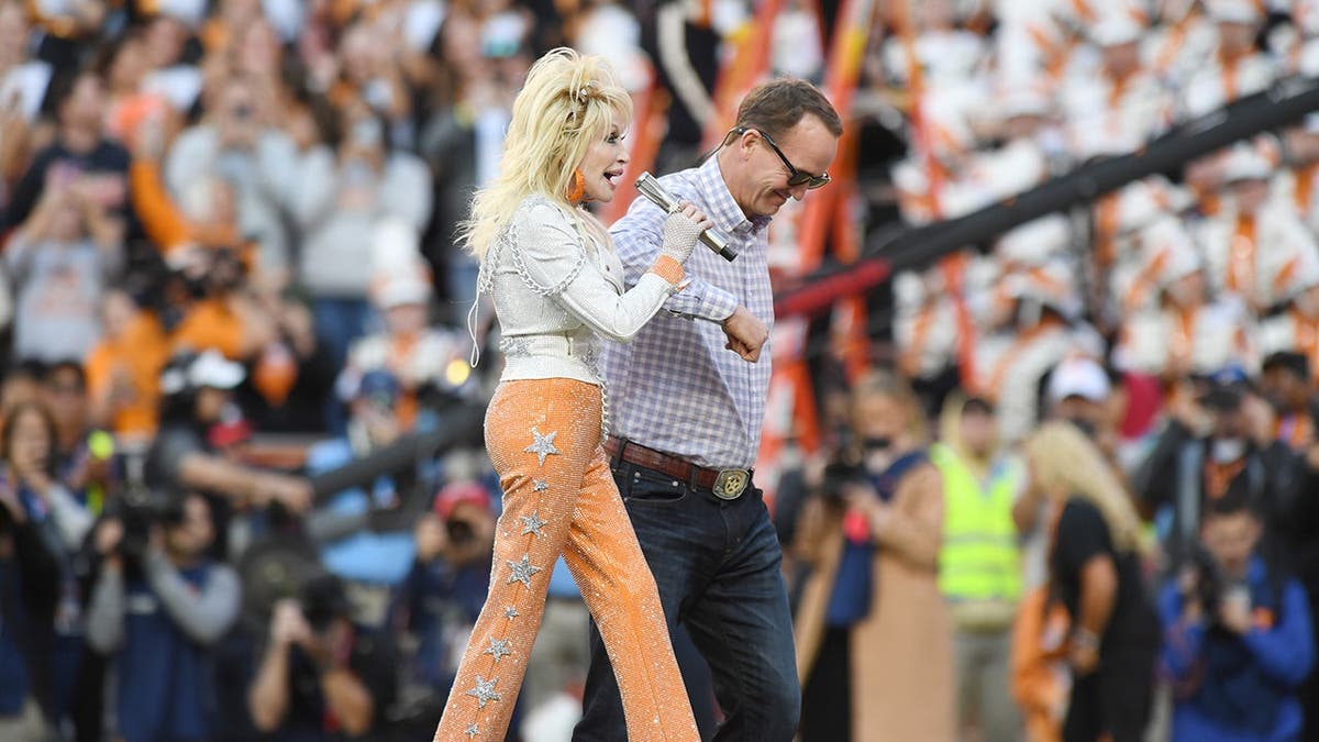 Dolly Parton and Peyton Manning walk off the field at Neyland Stadium.