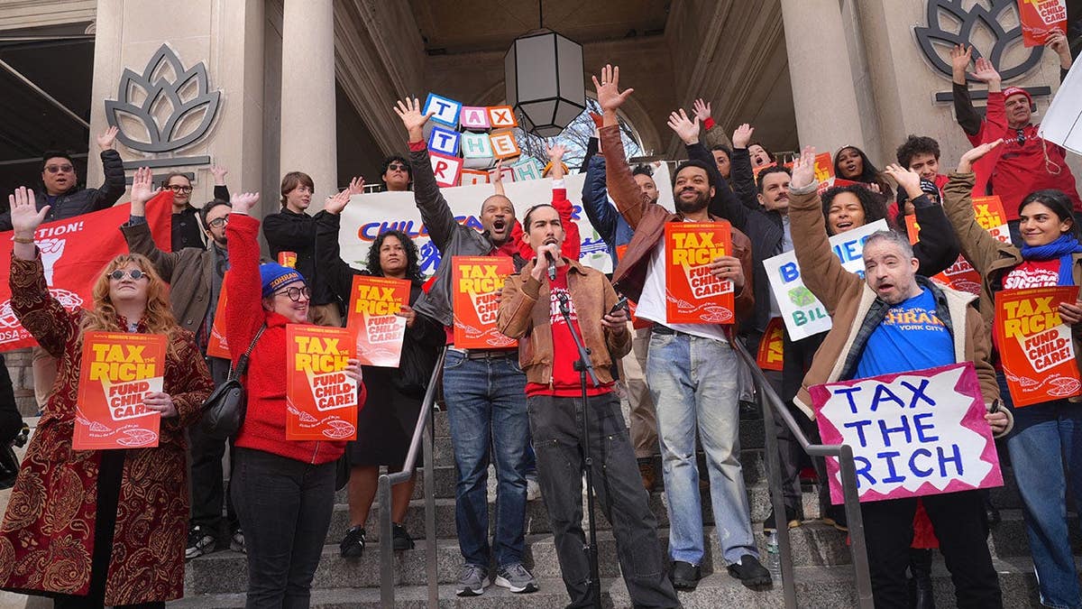 NYC-DSA members hold signs during a rally in Union Square.
