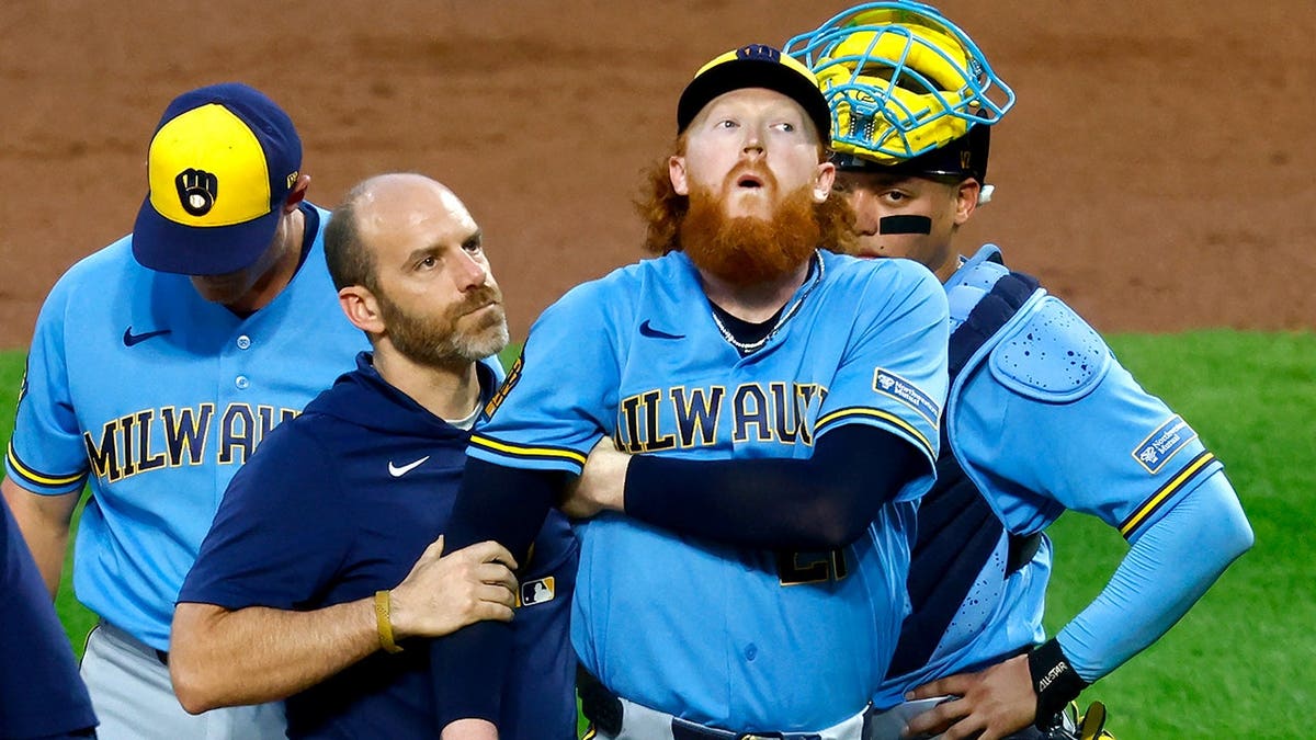 Dustin May reacts after being hit by a batted ball during a baseball game.