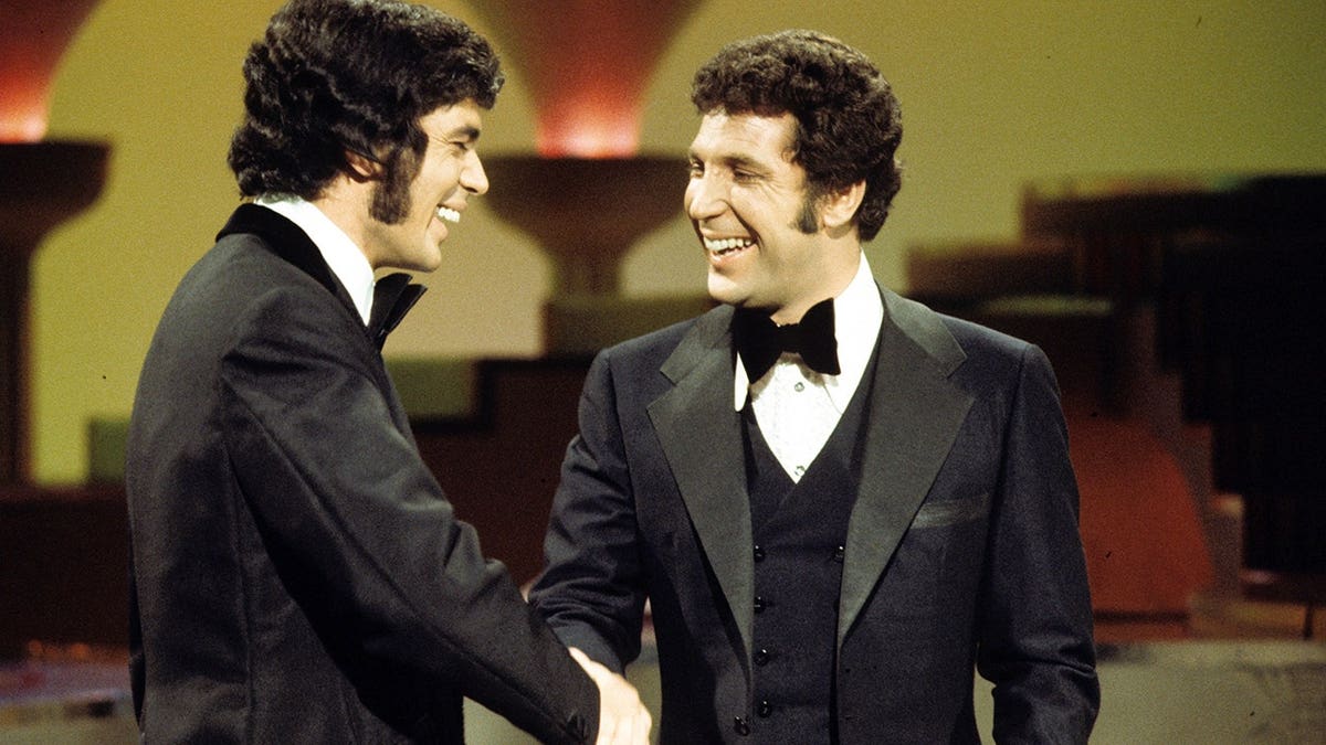 Engelbert Humperdinck and Tom Jones shake hands.