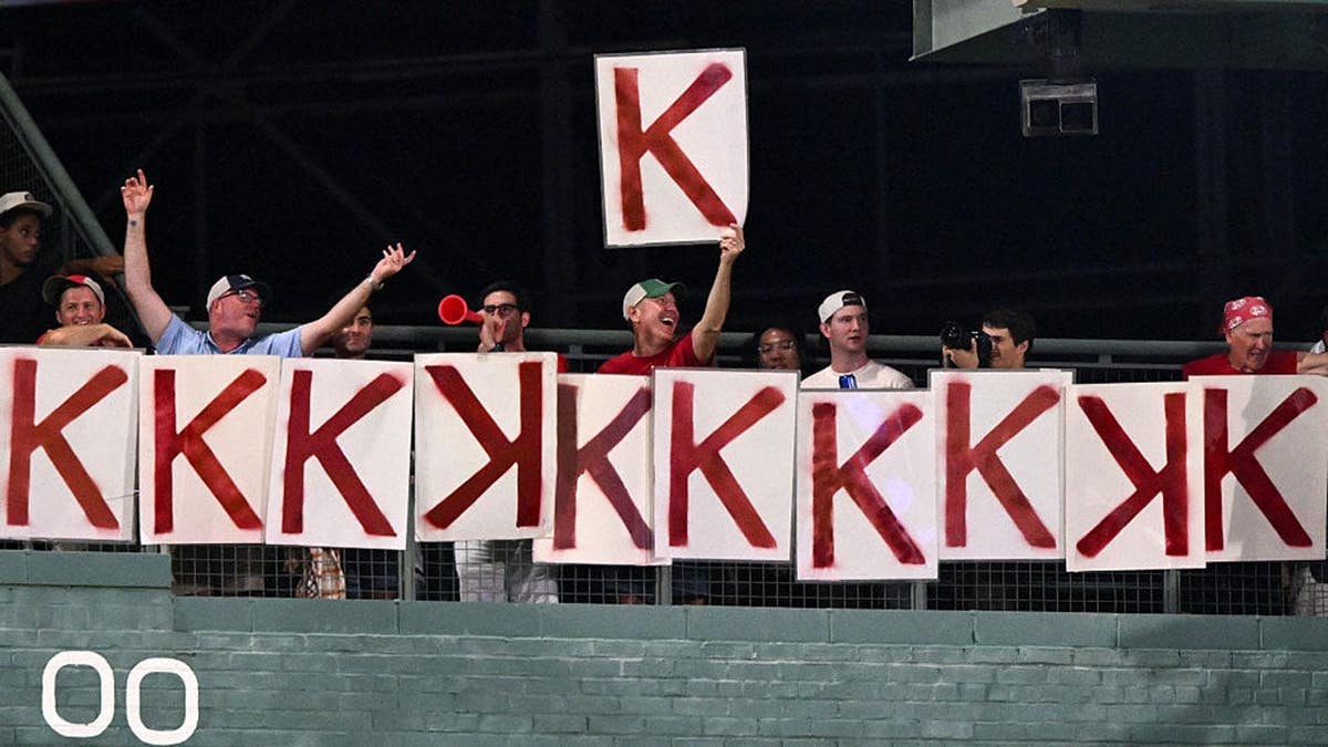 Fans hold up a K sign in the stands at Fenway Park during a Red Sox game.