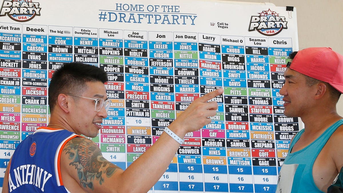 Attendees fill out a fantasy football draft board at a pool party.