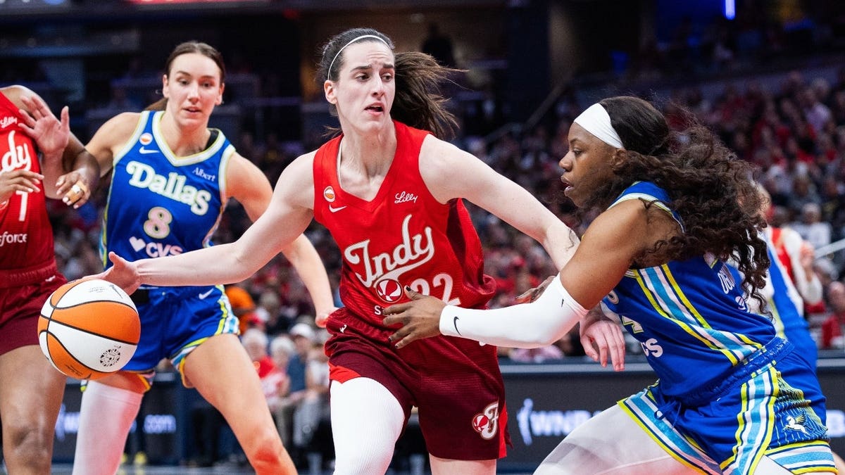 Indiana Fever guard Caitlin Clark dribbles the ball vs. Dallas Wings guard Arike Ogunbowale at Gainbridge Fieldhouse.