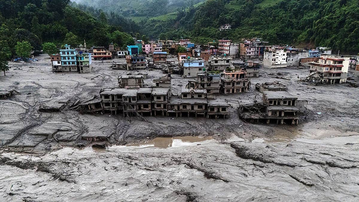 Damaged buildings and houses covered in mud beside the Likhu River in Devighat, Nepal.