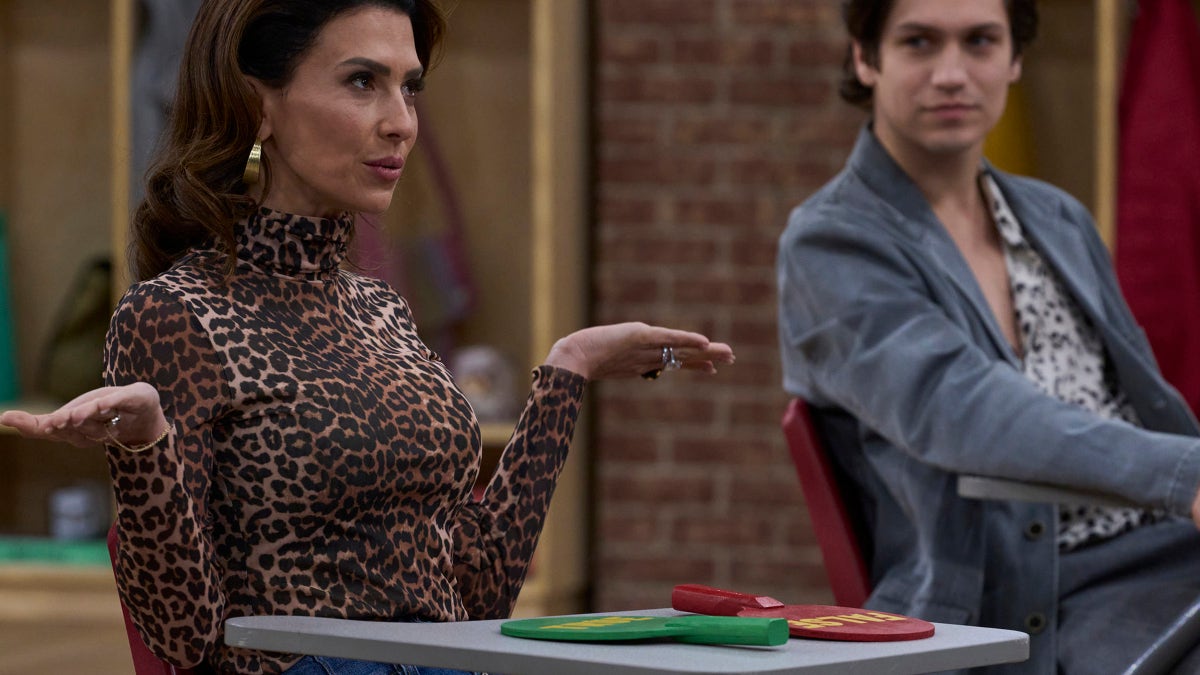 Hilaria Baldwin and Chase Hudson seated at classroom desks on a television set.