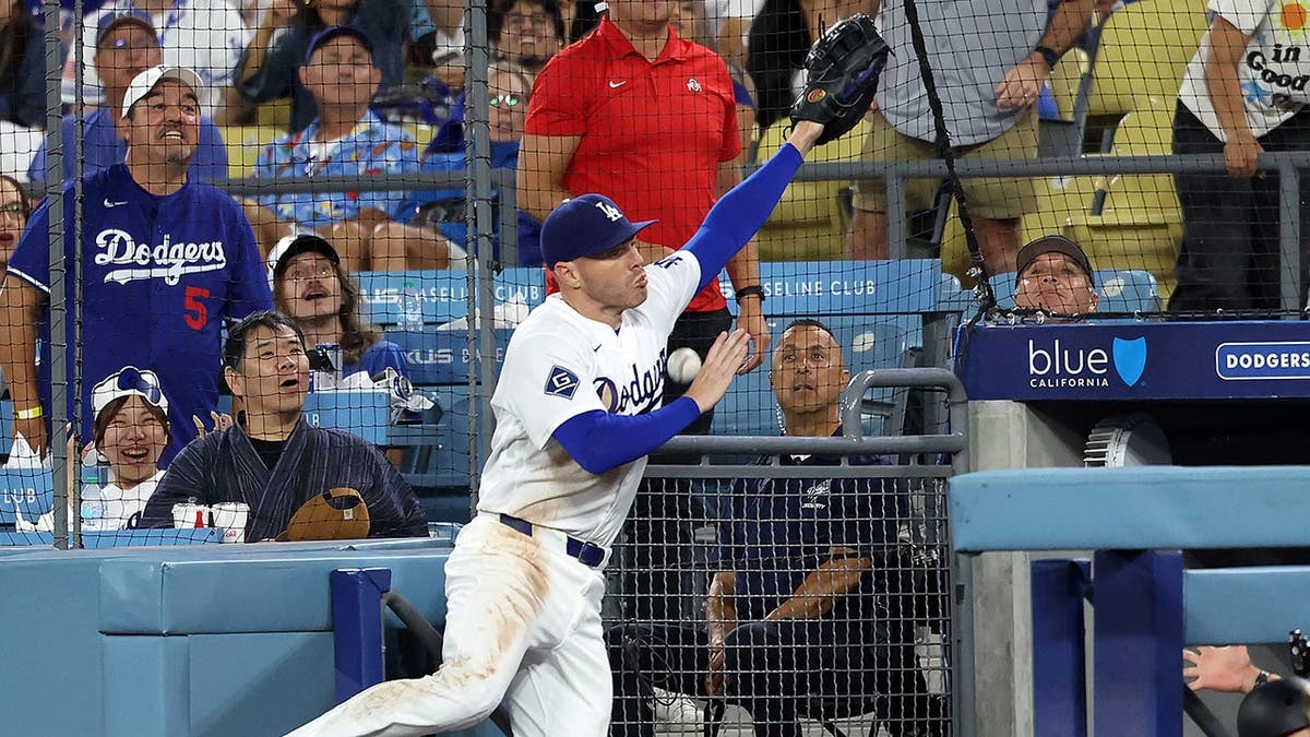 Freddie Freeman se cae al banquillo mientras persigue una bola de foul durante un partido de béisbol.