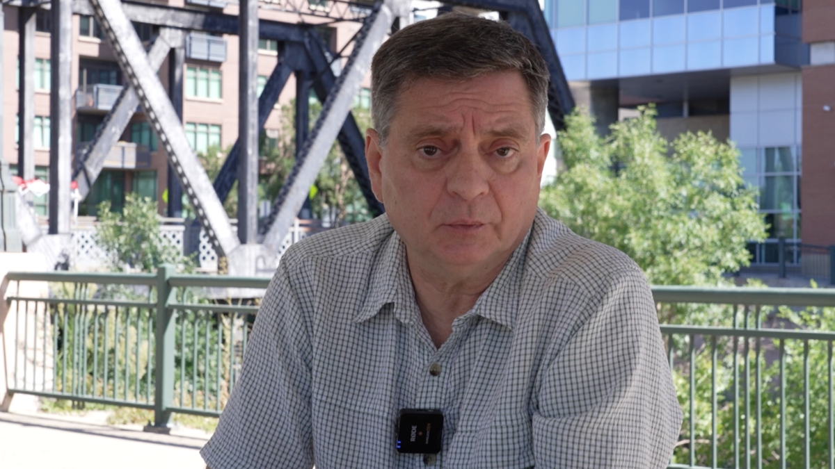 Man talking to camera in white and gray short sleeve plain button up