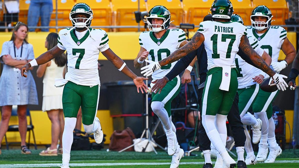 Geno Smith greets New York Jets teammates before a preseason game.
