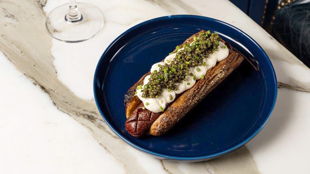 The Golden Glizzy hot dog sits on a plate.